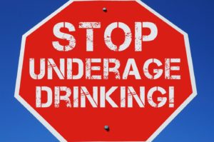 A large red stop sign telling people to stop underage drinking.