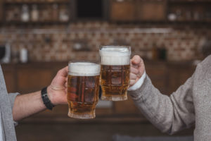 Two adults toasting mugs of beer.