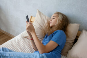 teen girl browsing social media while lying on her bed in the bedroom. Communication of modern children