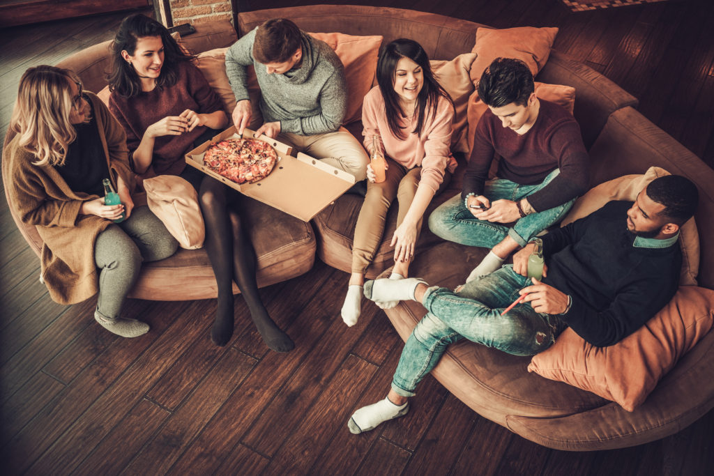 A diverse group of college students eating pizza.