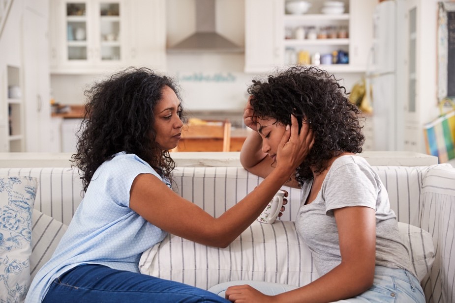 An African-American mother and daughter talking on the couch.