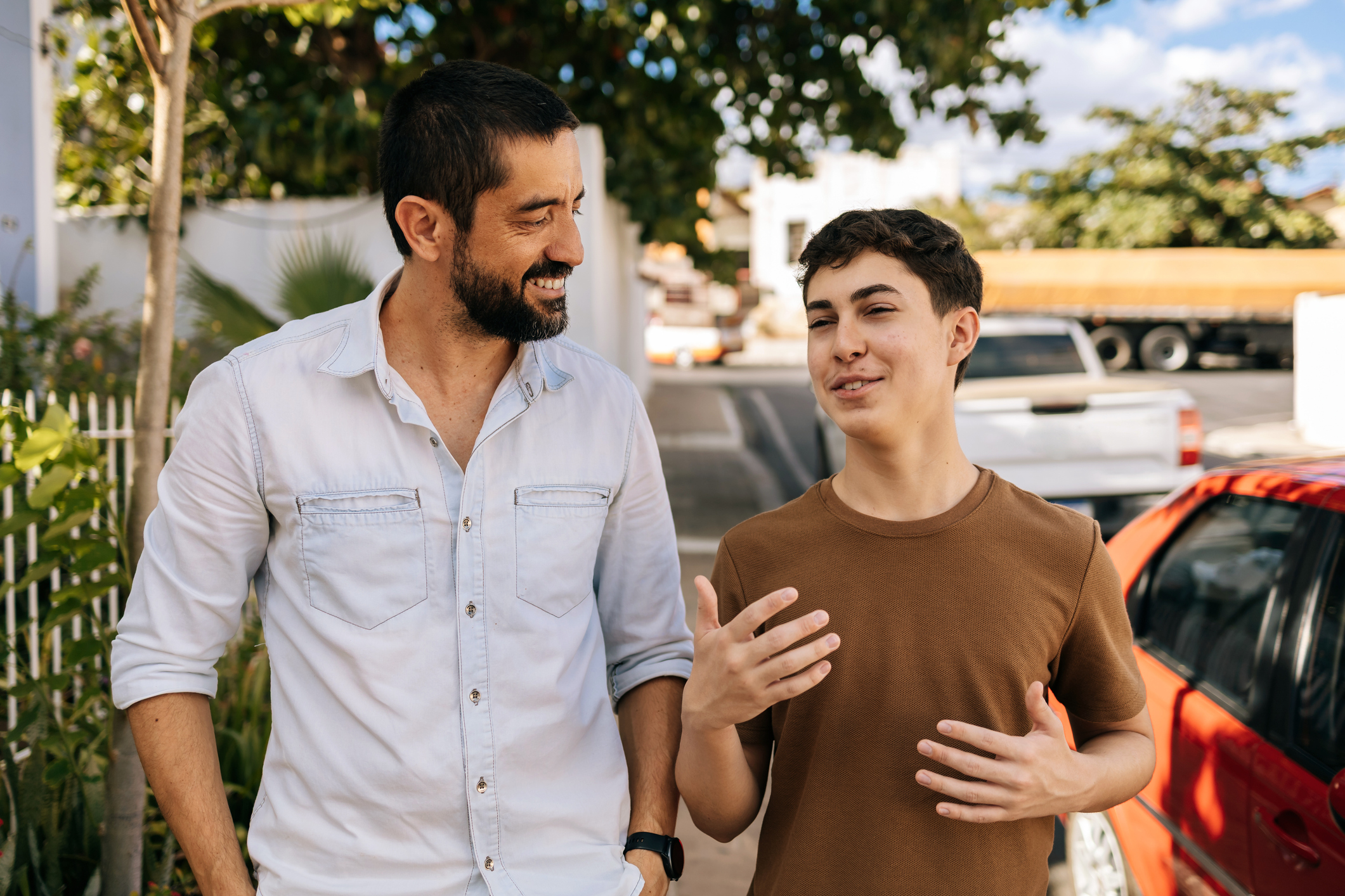 Teenage son speaks while his father listens attentively during an outdoor walk, highlighting active listening, empathy, guidance, emotional awareness, and family wellbeing