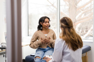 Young adult female patient gestures while explaining her mental health struggles with the doctor
