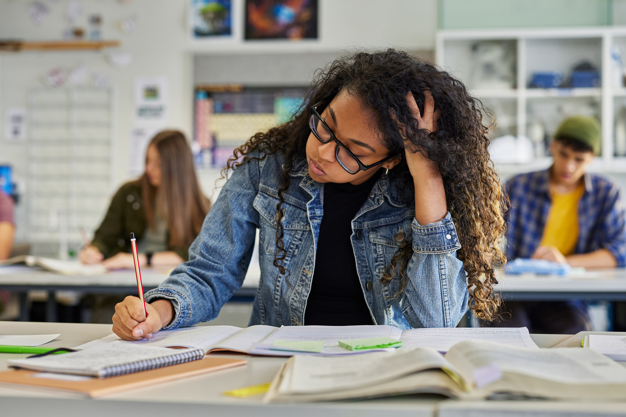 Tired female student writing in class during exam.