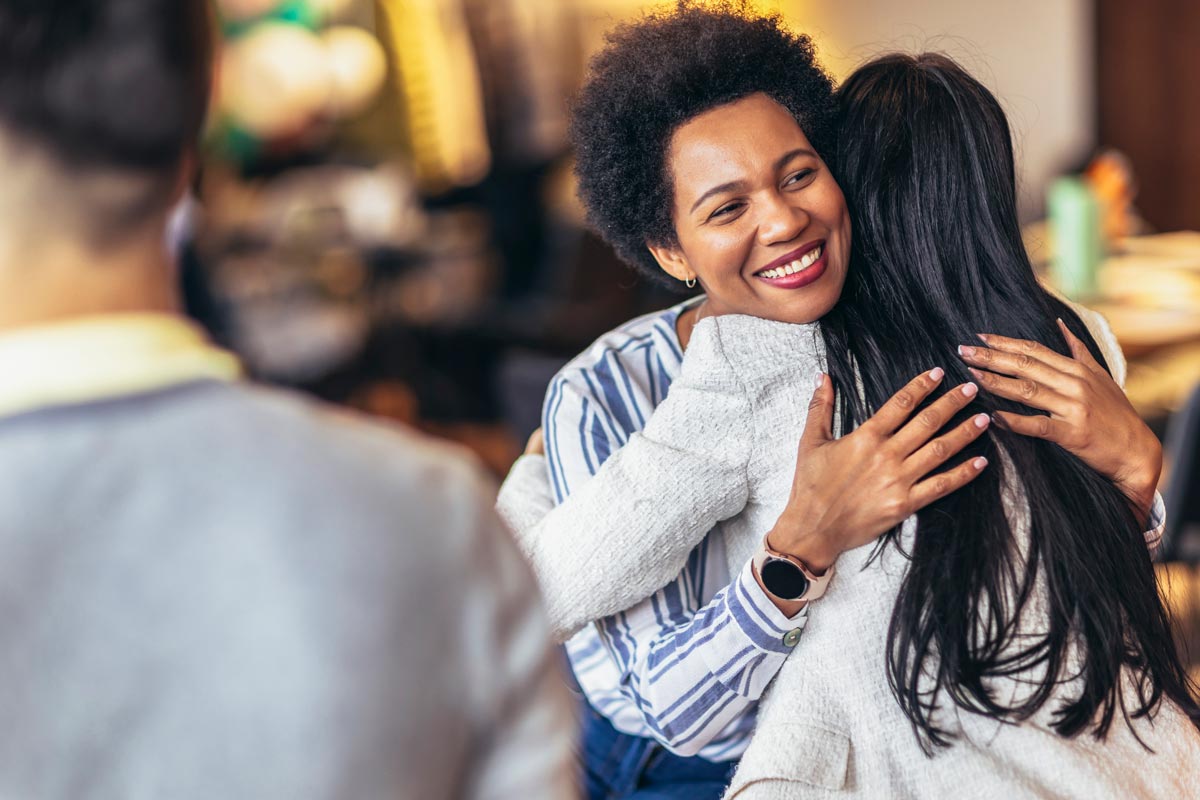 A happy embrace of a female adult and a female teen in thin crowd